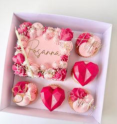 pink cupcakes in a box with the word resna written on them and decorated with flowers