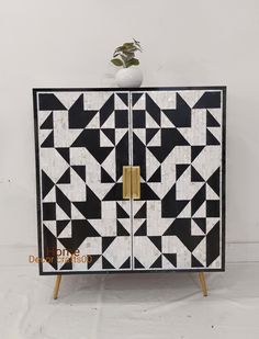 a black and white cabinet with geometric designs on the front, gold handles and doors