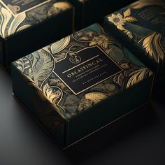 three boxes that are sitting side by side on a table with black and gold designs