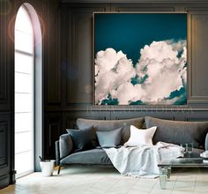 a living room filled with furniture and a large painting on the wall above it's windows