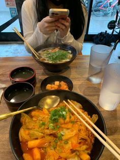 a woman taking a selfie while eating food with chopsticks in front of her