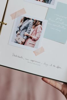 a hand holding an open photo book with photos on the pages and words written in cursive writing