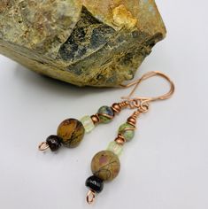 Fall colors of green, brown, earth tone bead with colors of reds, orange, black, dark blue, copper seed bead accents, dark brown doughnut bead at the bottom with handcrafted french ear wires. Brown Earrings With Natural Stones And Round Beads, Adjustable Earthy Beaded Earrings As Gift, Bohemian Brown Hand Wrapped Earrings, Bohemian Brown Hand-wrapped Earrings, Bohemian Hand Wrapped Brown Earrings, Earthy Beaded Dangle Earrings As Gift, Brown Wire Wrapped Drop Beaded Earrings, Brown Wire Wrapped Drop Earrings, Adjustable Green Beaded Earrings With Natural Stones