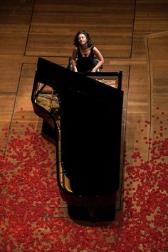 a woman sitting on top of a piano in a room filled with rose petals,