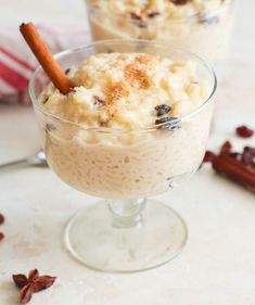 two glasses filled with ice cream and topped with cinnamon stick garnish on a table