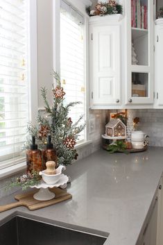 a kitchen with white cabinets and gray countertops is decorated for the holiday season,