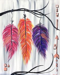 three colorful feathers hanging from a tree branch