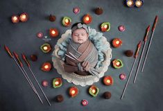 a baby wrapped in a blanket is surrounded by candles and crocheted doily