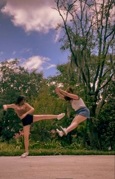 two girls are playing with a frisbee in the park together, one is jumping