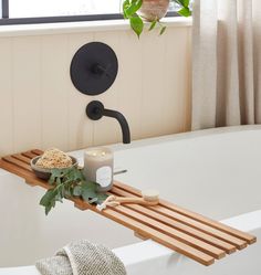 a bathtub with a candle, soap and brush sitting on it next to a potted plant