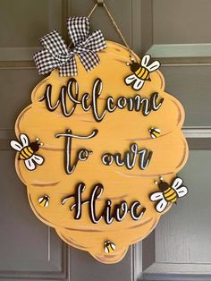 a wooden sign that says welcome to our hives on the front door with some bees hanging from it