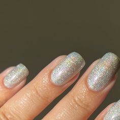 a woman's hand with white and silver nail polish