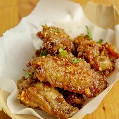 some fried food is in a basket on a wooden table with white napkins and green garnishes