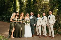 a group of people standing next to each other in front of some trees and bushes