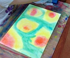 a child is painting on paper with colored watercolors in the process of making an art project