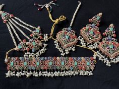 The jewelry set being offered here is a traditional Noratan bridal set, often worn during weddings or other formal occasions in Indian and Pakistani cultures. It is a multicolor set that can complement with many outfits and can be worn at many formal occasions. Here's a detailed description of this Navratan set  - **Noratan Bridal Choker The choker is  grand and intricate, typical of Noratan designs. It  features a combination different color embedded beads on a golden background.  The design is Traditional Multicolor Jewelry For Traditional Ceremonies, Traditional Multicolor Jewelry For Ceremonies, Traditional Multicolor Tilla Jhumkas, Intricate Design Sets For Wedding And Navratri, Traditional Kundan Bridal Earrings For Ceremonies, Traditional Chandbali Bridal Sets With Stone Work, Traditional Jewelry Sets For Eid Ceremonies, Wedding Sets With Stone Work In Multicolor, Bollywood Style Heavy Multicolor Sets