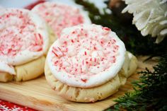 three cookies with white frosting and sprinkles on a cutting board