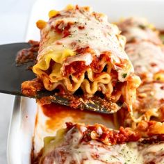 a spatula is lifting up some lasagna from the casserole dish