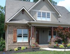 a gray house with wooden shutters on the front door and windows in the side