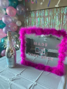 a pink frame sitting on top of a white table next to a bottle of champagne