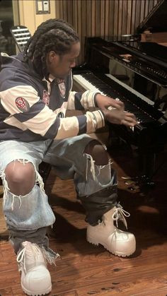 a man sitting on the floor next to a piano