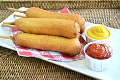 three fried food items on a plate with dipping sauces