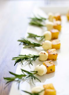 small appetizers are arranged on a white plate with green garnishes