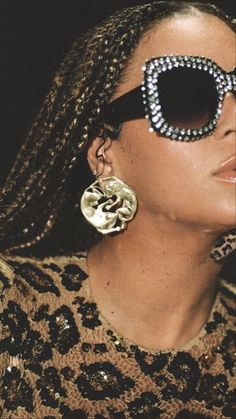 a close up of a person wearing sunglasses with beads on their face and hair in braids