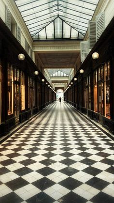 two people are walking down the hallway in an old building with checkered flooring