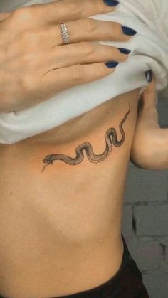 a woman's stomach with a snake tattoo on it