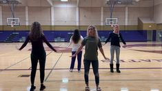 four girls are standing in a gym with their arms out and one girl is holding her hands out