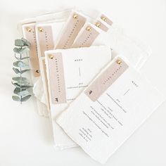 five wedding place cards on top of each other next to some eucalyptus leaves and greenery