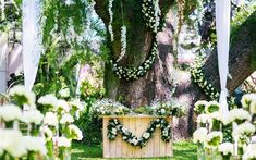 an outdoor ceremony setup with flowers and greenery on the trees, surrounded by lush green grass