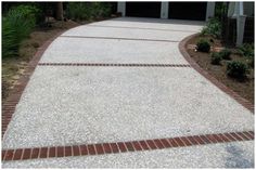 a driveway with brick edging and landscaping around it