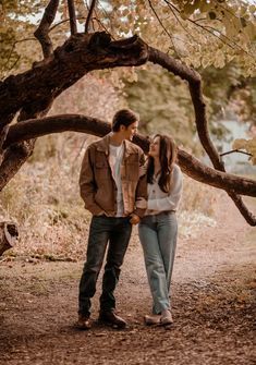 a man and woman standing next to each other under a tree