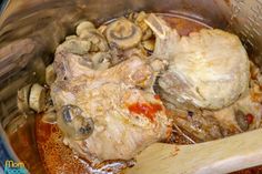 meat and mushrooms cooking in a pot with a wooden spoon