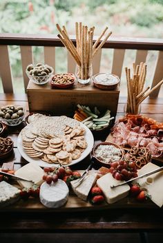 a wooden table topped with lots of different types of cheeses and crackers on top of it