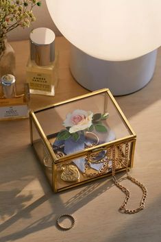 a gold jewelry box sitting on top of a wooden table next to a white lamp