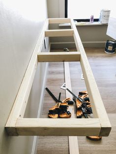 there are many pairs of shoes on the floor in front of an open drawer that is holding tools