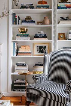 a striped chair in front of a bookshelf filled with books