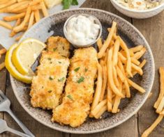 fried fish and fries with tartar sauce on a plate next to lemon wedges