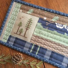 a close up of a piece of fabric on a wooden floor with pine cones and needles