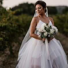 a woman in a wedding dress holding a bouquet and looking at the camera with her eyes closed