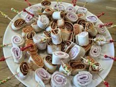 a white plate topped with lots of food on top of a wooden table next to candy sticks