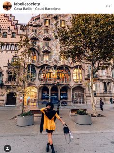 a woman is walking in front of a building with many windows and balconies