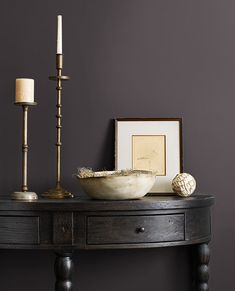 a wooden table with a bowl and two candles on it next to a framed photograph