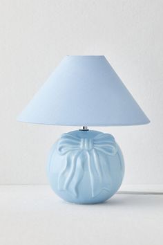 a blue ceramic lamp with a white shade on the base and a light blue fabric shade on the top