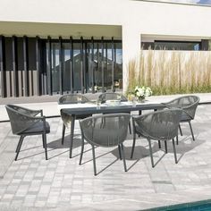 an outdoor dining table and chairs next to a swimming pool