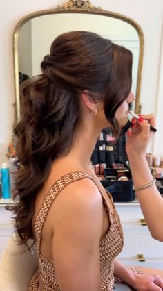 a woman sitting in front of a mirror brushing her teeth