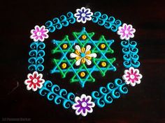 an artistic design made with colored thread and beads on a black table top, in the shape of a flower